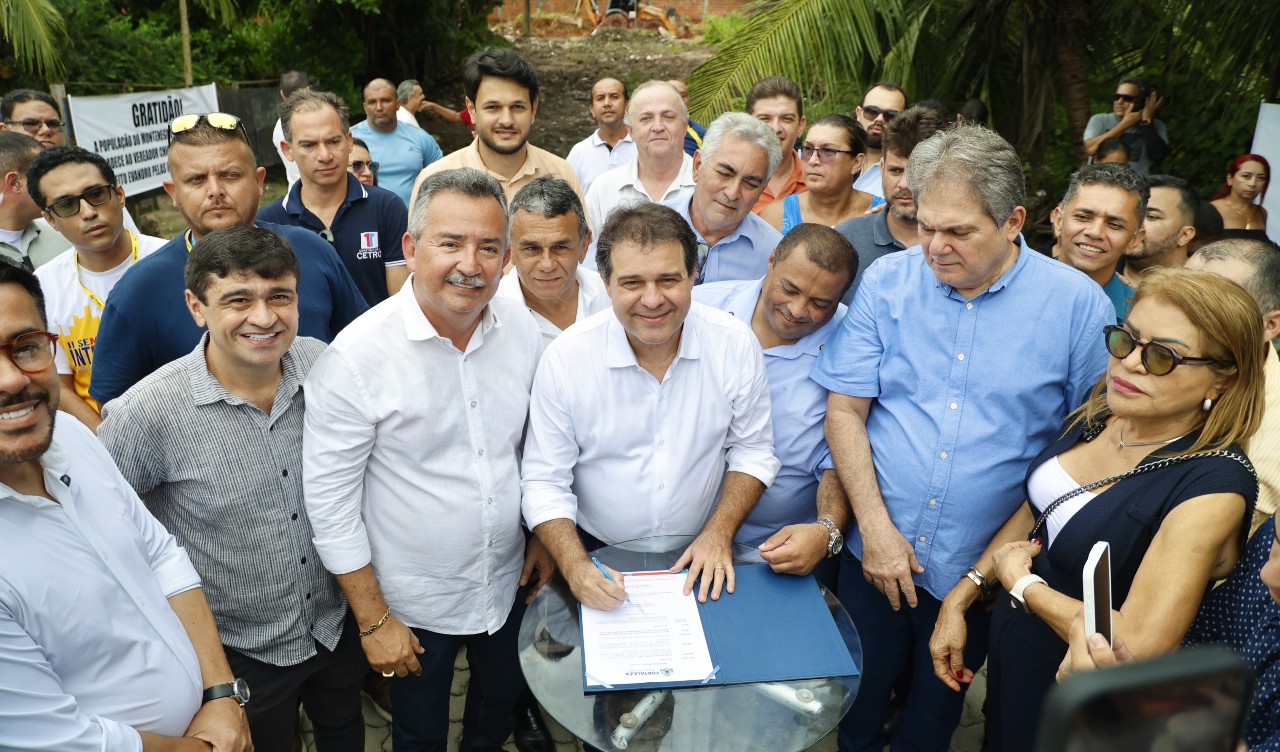 prefeito assina a ordem de serviço, cercado por apoiadores no local onde será construída a ponte